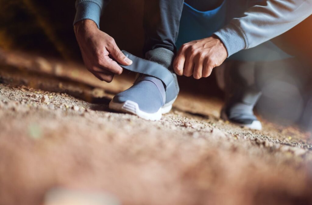 An older adult straps on their adjustable sneakers for additional support and comfort while walking.