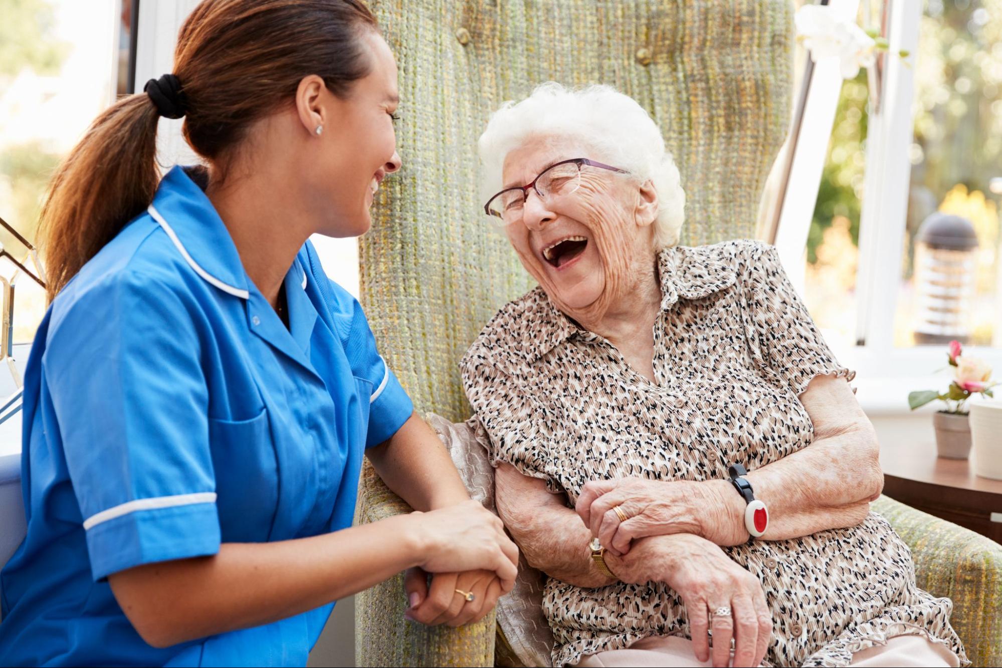 A senior woman laughing with her caregiver in memory care.