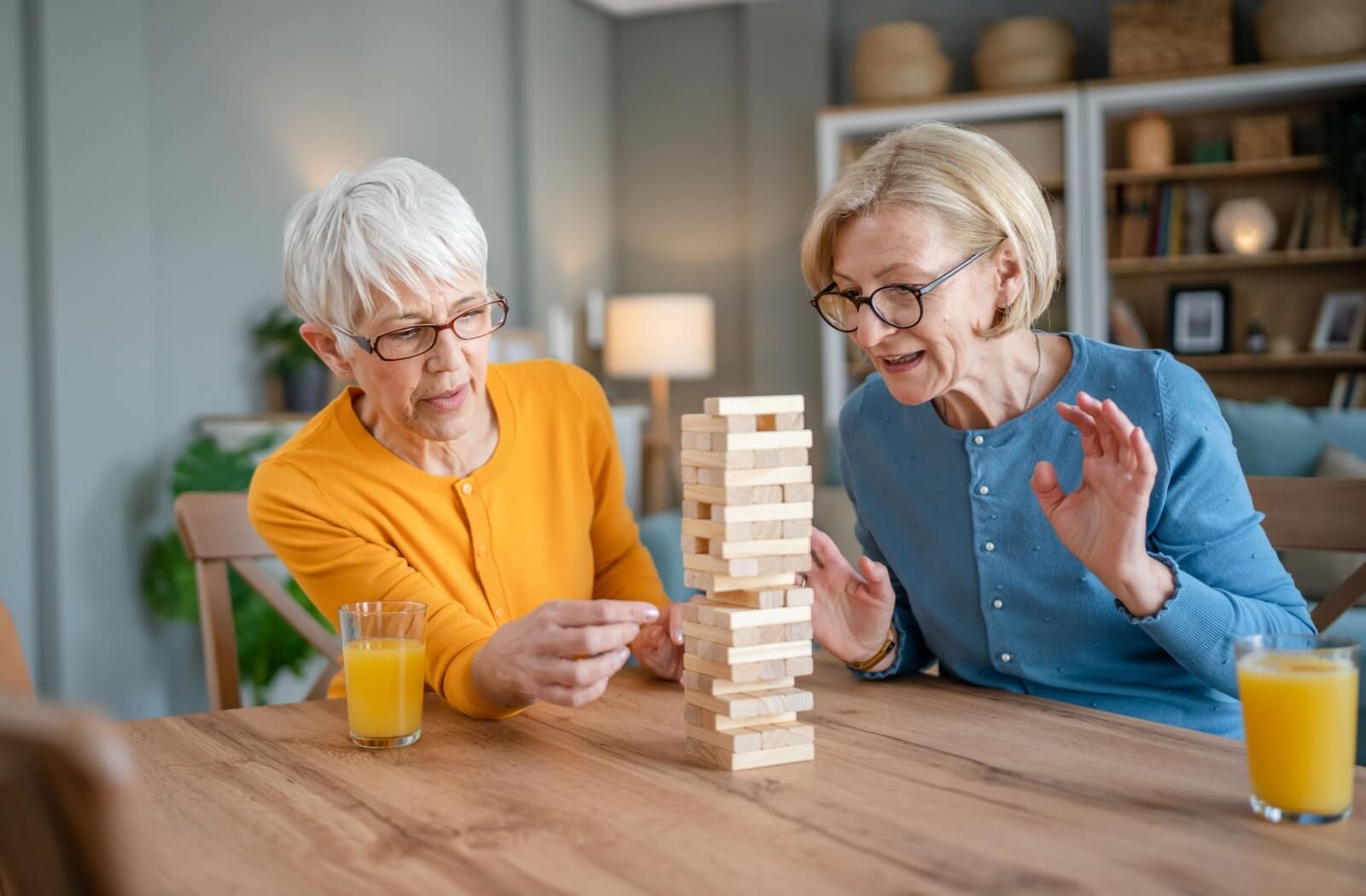 Two older adult friends play Jenga together during a respite care stay.