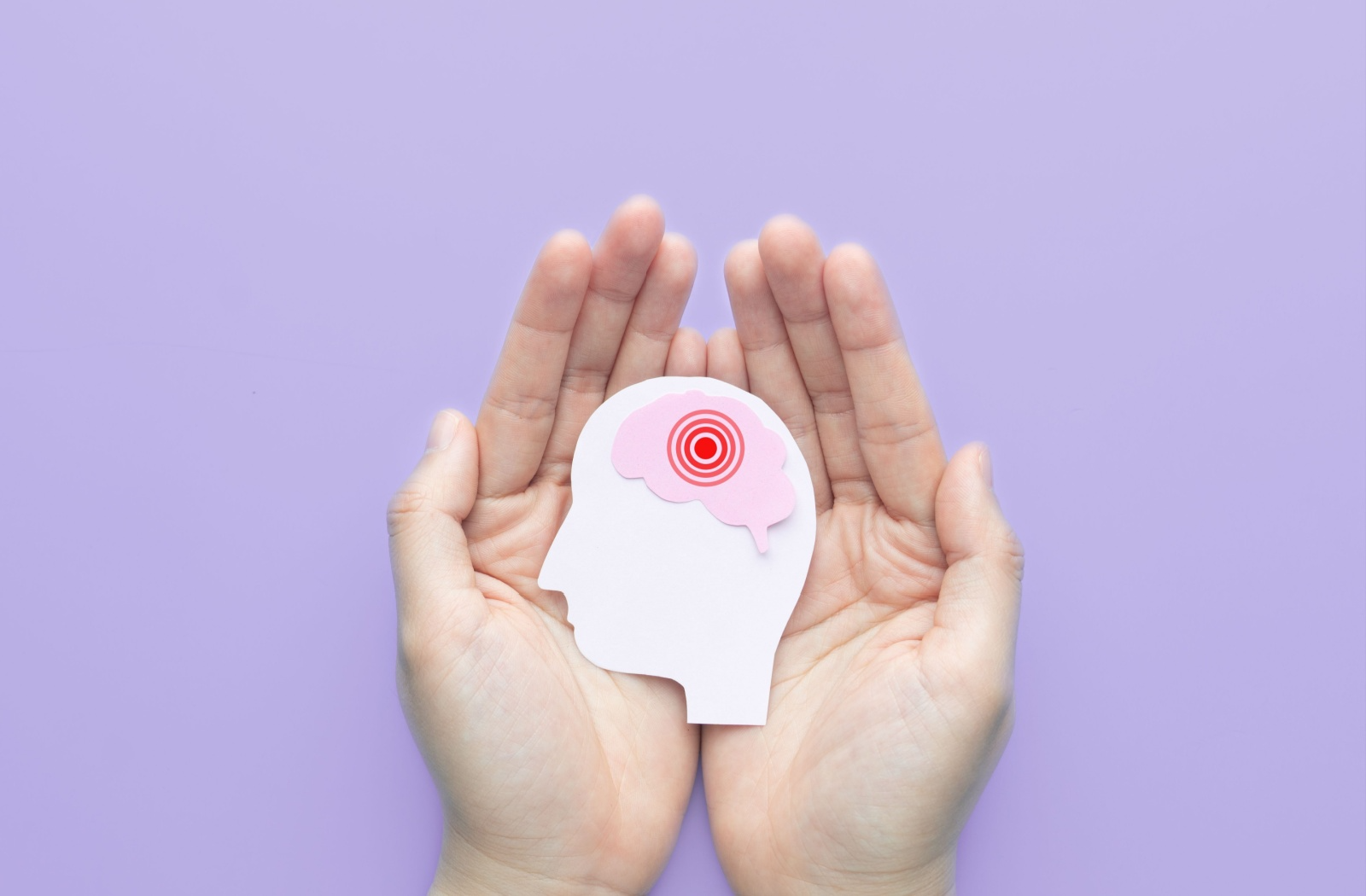 Two hands holding a paper cutout diagram of a head and brain to represent dementia.