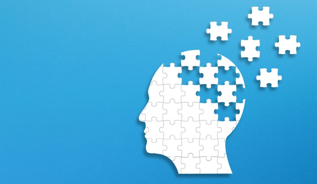 a head made of puzzle pieces on a blue background. Some of the puzzle pieces have been removed
